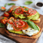 Healthy tomato toast with mozzarella, avocado, and basil on sourdough bread