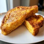 Two slices of golden-brown 40 g Protein French toast stacked on a white plate, ready to eat.