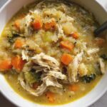 Overhead shot of a bowl of Anti-Inflammatory Chicken Soup with chicken, carrots, and herbs.