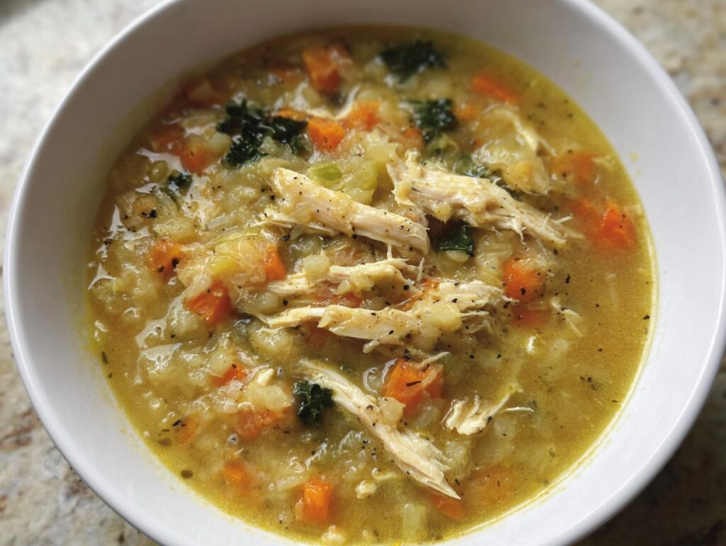 A bowl of homemade Anti-Inflammatory Chicken Soup with shredded chicken, carrots, and greens.