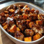 Close-up of BBQ Chicken Sweet Potato dish, featuring chicken and sweet potatoes coated in barbecue sauce, garnished with herbs.