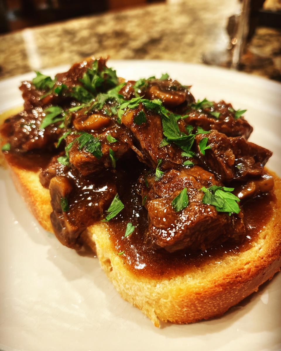 Close-up of Best Beef Manhattan on toasted bread, topped with gravy, mushrooms, and fresh parsley.