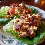 Two servings of BLT Chicken Salad served in crisp lettuce cups, topped with bacon and tomatoes.