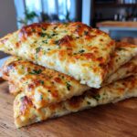 A stack of cheesy tortilla garlic bread slices, topped with melted cheese and herbs. Delicious CHEESY TORTILLA GARLIC BREAD recipe.