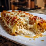 Close-up of Chicken Manicotti Alfredo, filled with chicken and topped with melted cheese on a white plate.
