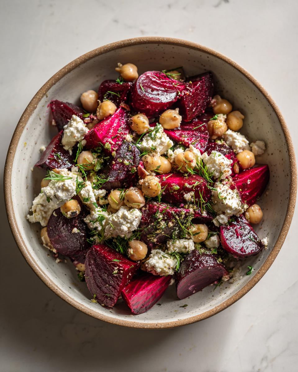 Overhead shot of a vibrant Chickpea, Beet and Feta Salad in a ceramic bowl, garnished with fresh herbs.
