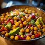 A vibrant bowl of Chickpea Feta Avocado Salad with red onion and tomatoes.