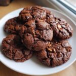 A plate of freshly baked Chocolate-Peanut Butter Cookies, topped with chocolate chunks.