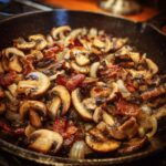 Close-up of Cowboy Mushrooms with bacon and onions sizzling in a cast iron skillet.