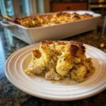 A serving of Dolly's Chicken and Stuffing Casserole on a white plate, with the casserole dish in the background.