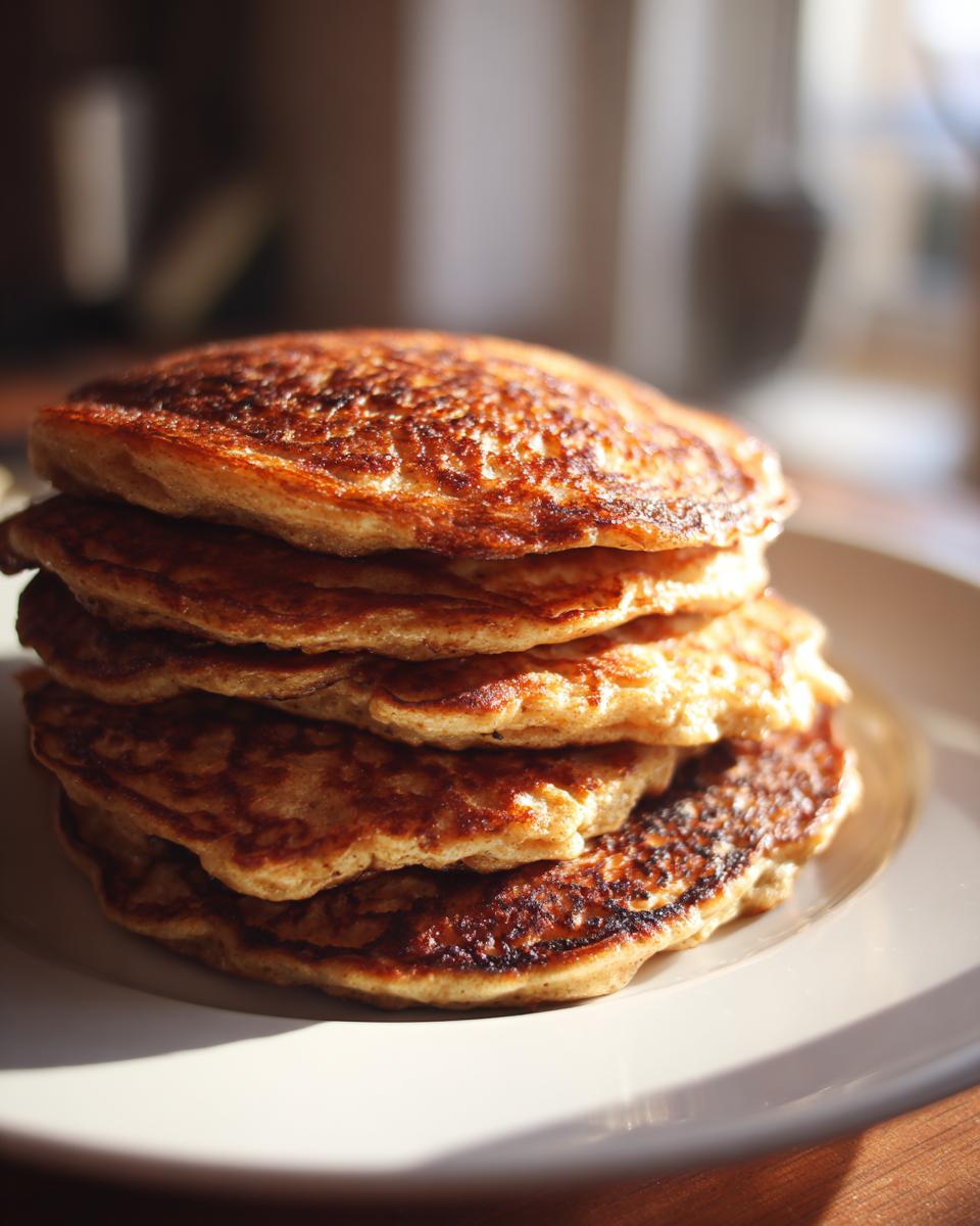 A stack of golden brown Energizing Red Lentil Pancakes on a white plate, ready to be enjoyed.