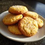 A stack of freshly baked French Salted Butter Cookies on a plate, sprinkled with coarse salt.