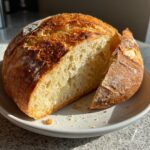 Loaf of fresh bread on a plate, a key ingredient for making delicious Goat Cheese & Honey Bites.