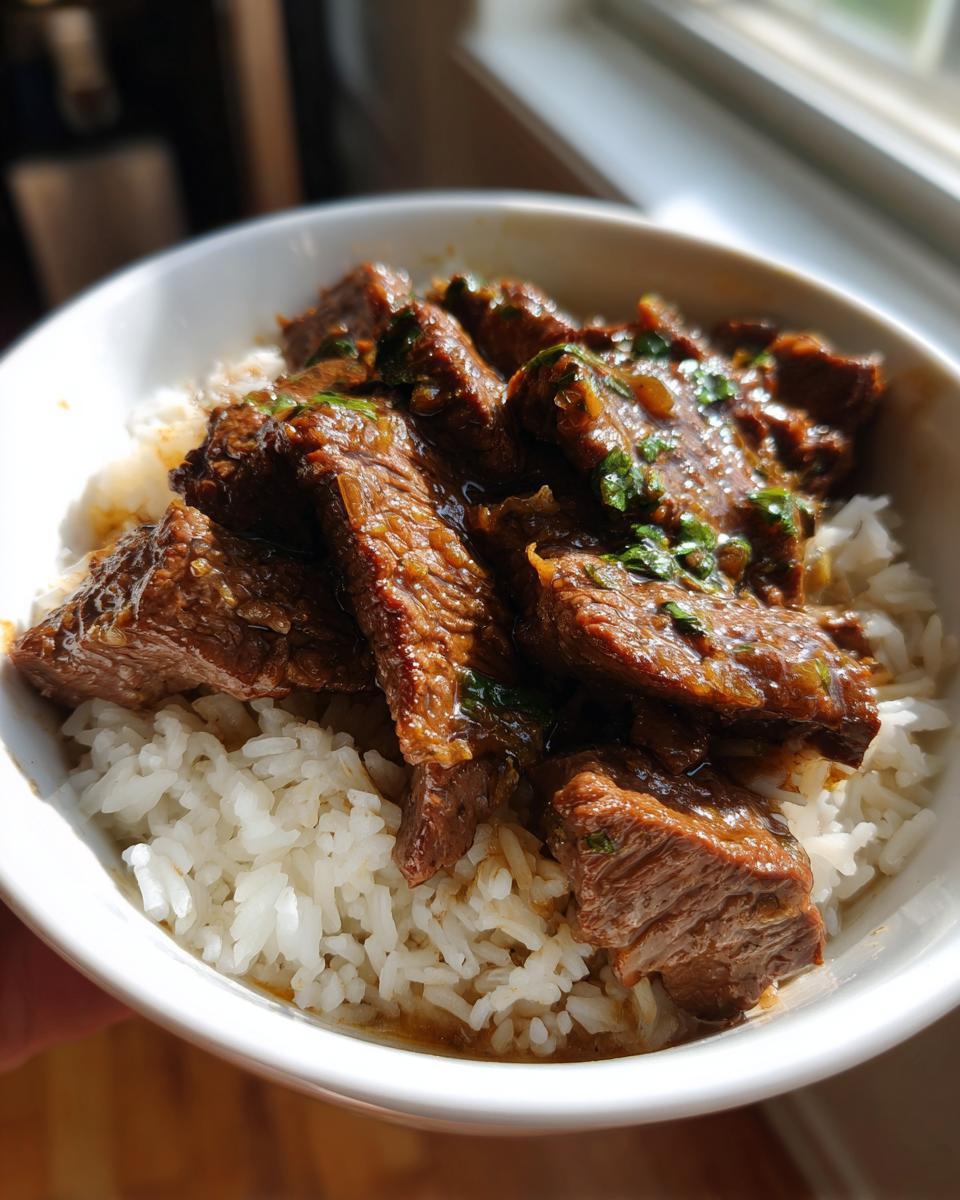 A delicious bowl of Garlic Butter Beef and Rice, featuring tender beef pieces over fluffy white rice.