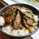 A delicious bowl of Garlic Butter Beef and Rice, topped with fresh herbs.