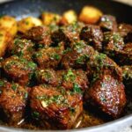 Close-up of Garlic Butter Beef bites with herbs and potatoes in a pan.