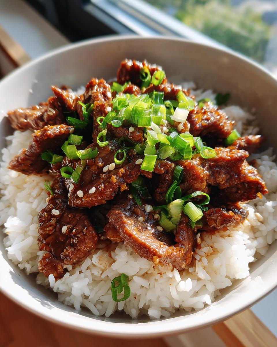 A delicious bowl of Garlic Butter Beef and Rice topped with green onions and sesame seeds.