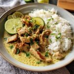 A delicious bowl of Ginger Lime Pork with Coconut, served with white rice and lime wedges.