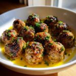 A bowl of delicious Greek Meatballs in Lemon Sauce, garnished with fresh herbs.