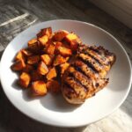 A plate of Grilled Chicken & Sweet Potato, with a grilled chicken breast and diced sweet potatoes.