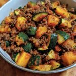 A bowl of savory ground beef zucchini dish with herbs and a rich sauce.