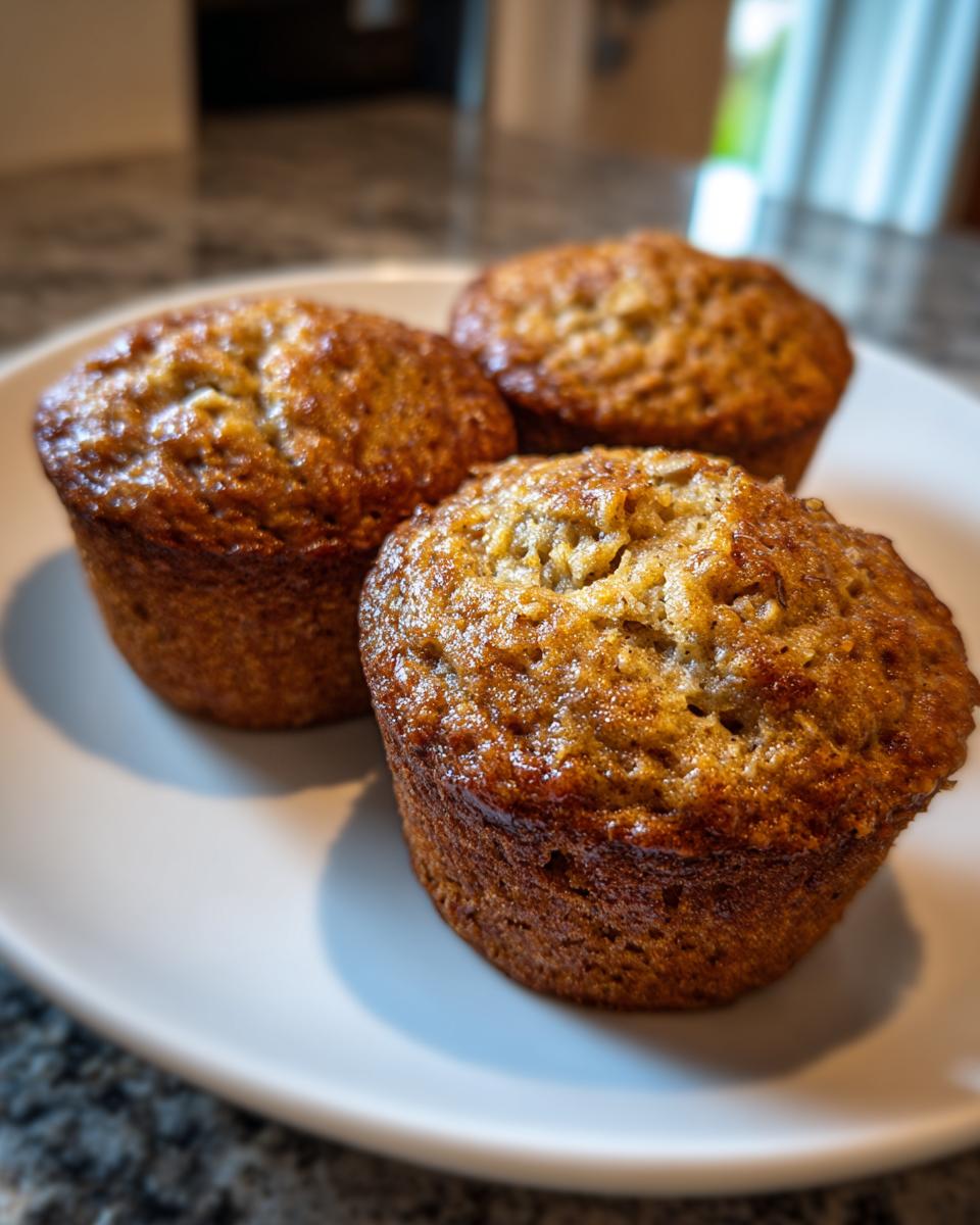 Three Healthy Banana Oatmeal Muffins arranged on a white plate, showcasing their golden-brown color and texture.