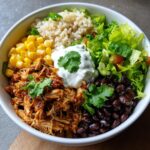 Overhead shot of a Healthy Chicken Taco Bowl with chicken, rice, beans, corn, lettuce, and sour cream.