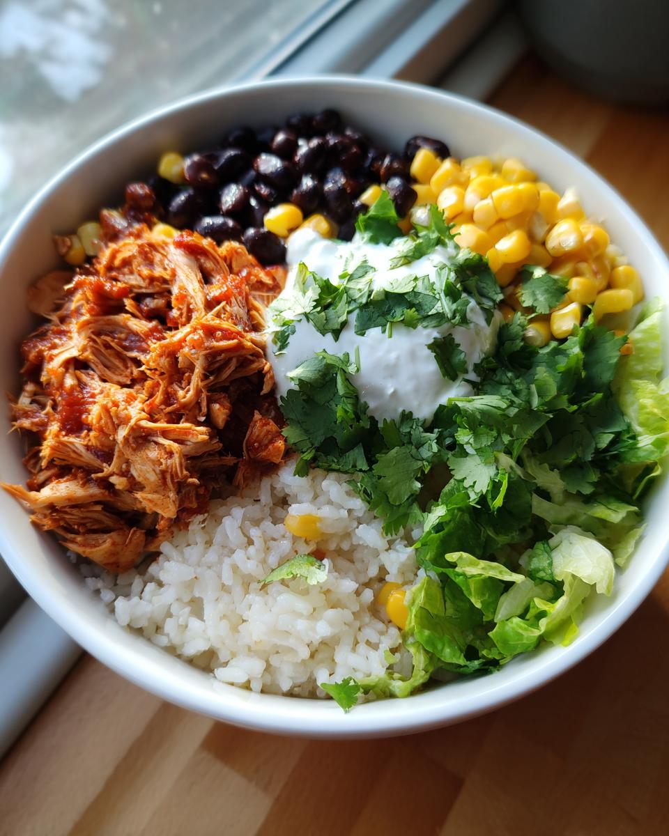 Overhead shot of a Healthy Chicken Taco Bowl with chicken, rice, beans, corn, lettuce, sour cream, and cilantro.