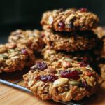 A stack of Healthy Nut Energy Cookies with oats, nuts, and dried cranberries on a cooling rack.