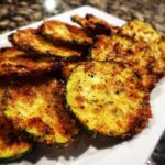 A plate of golden brown, crispy Healthy Zucchini Chips, seasoned and ready to eat.