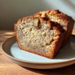 A slice of High Protein Banana Bread with Greek Yogurt, showing the texture and walnuts.