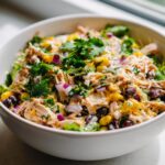 A vibrant bowl of High Protein Southwest Chicken Salad with chicken, corn, black beans, red onion, and cilantro.