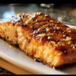 Close-up of a glazed Hot Honey Salmon fillet on a white plate, showcasing the texture and glaze.