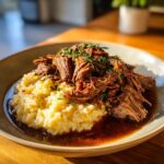 A plate of Italian Pot Roast & Parmesan Risotto, garnished with herbs and rich sauce.