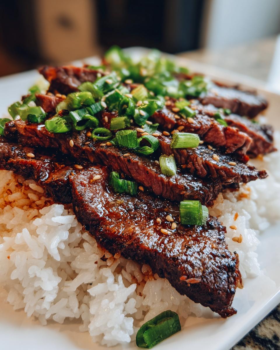 Close-up of Korean BBQ Steak Rice, featuring sliced steak over rice, garnished with green onions and sesame seeds.