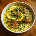 A bowl of Lemon Chicken Soup with orzo pasta, garnished with fresh lemon slices and parsley.