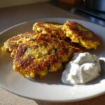 Golden Lemon Chickpea Patties served with a dollop of creamy yogurt sauce on a white plate.