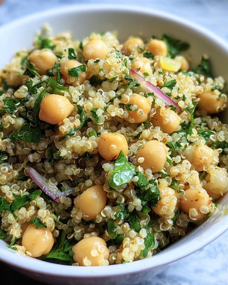 Close-up of a bowl of Lemon Herb Quinoa Chickpeas salad with fresh herbs and red onion.