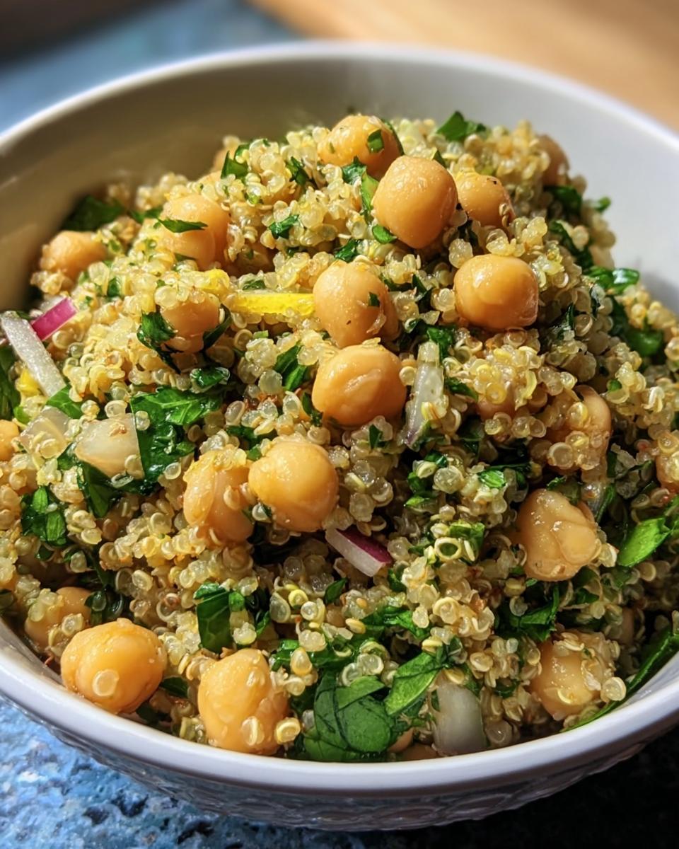 Close-up of Lemon Herb Quinoa Chickpeas in a white bowl, showing chickpeas, quinoa, herbs, and red onion.