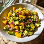 A vibrant bowl of Mango Cucumber Salad with Avocado, featuring diced mango, cucumber, avocado, and red onion.