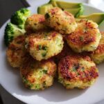 A plate of golden brown Nutritious Chicken Broccoli Nuggets, served with fresh broccoli and avocado slices.