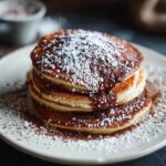 Stack of pancakes with chocolate and powdered sugar, not related to Keto Philly Cheesesteak Rolls.