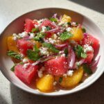 A vibrant bowl of Peach Watermelon Salad with feta, red onion, and mint.