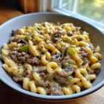 A delicious bowl of Philly Cheesesteak Mac & Cheese with pasta, beef, peppers, and mushrooms.
