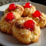 Close-up of Pineapple Upside-Down Cookies topped with a cherry on a plate.