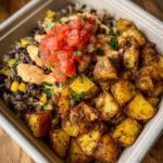 A prepared Potato Taco Bowl with rice, beans, corn, salsa, sauce, and roasted potatoes.