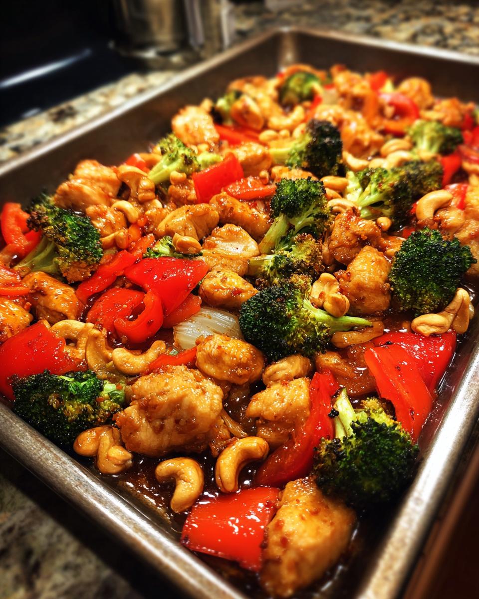 A sheet pan filled with Sheet Pan Cashew Chicken, featuring chicken, broccoli, red peppers, and cashews.
