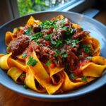 A bowl of Short Rib Ragu with Pappardelle, garnished with fresh parsley and parmesan cheese.