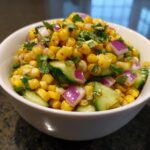 A bowl of vibrant Street Corn Cucumber Salad with corn, cucumber, red onion, and cilantro.