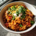A bowl of Taco Rice Soup topped with sour cream, cheese, and cilantro.